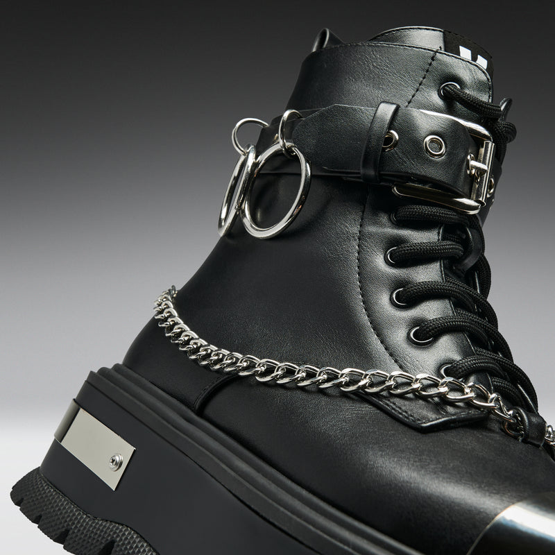 Black leather boot with chain detail on a gradient background