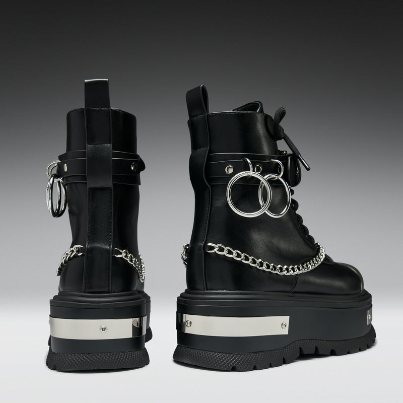 Black platform boots with chain details on a gradient background