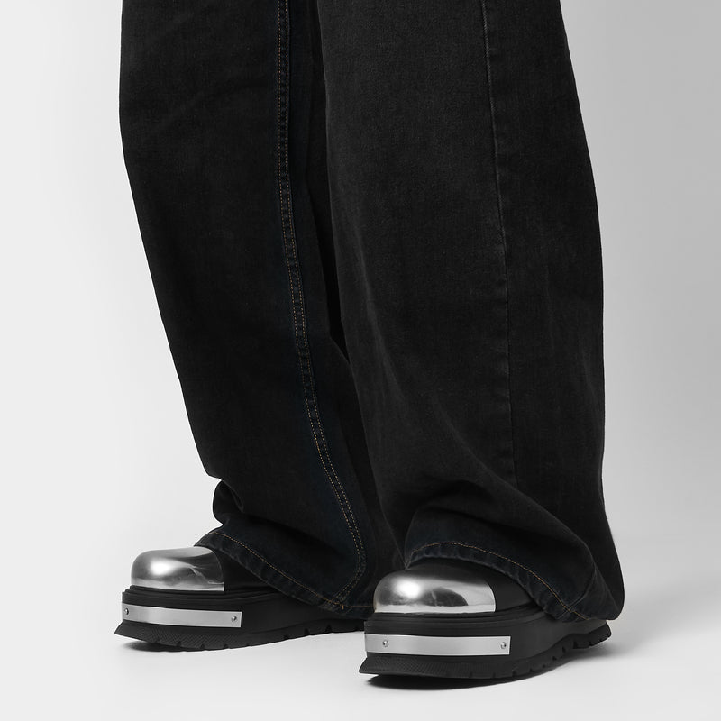 Model wearing jeans and black high-top boots with chain details on a gradient background
