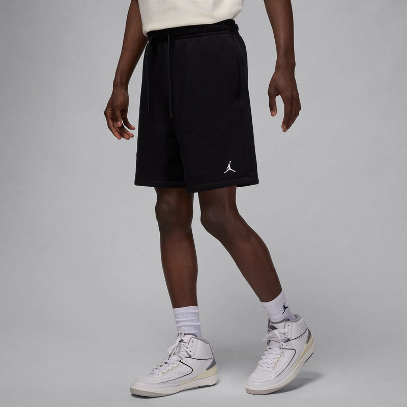 Men's black fleece shorts worn with white sneakers; drawstring and side Jordan logo.