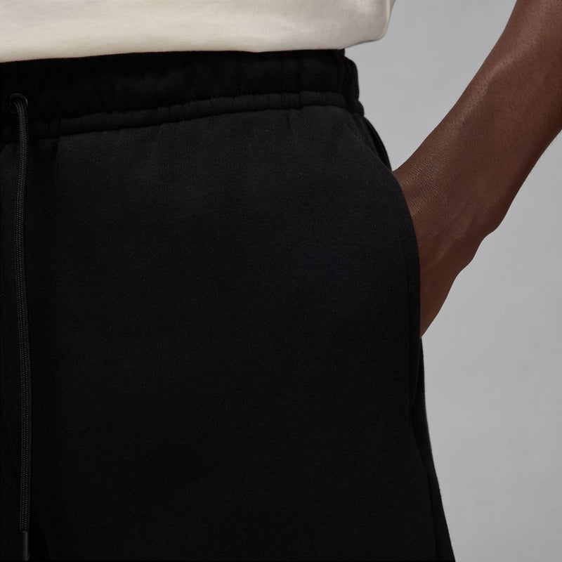 Men's black fleece shorts waistband detail with drawstring and side seam pocket.