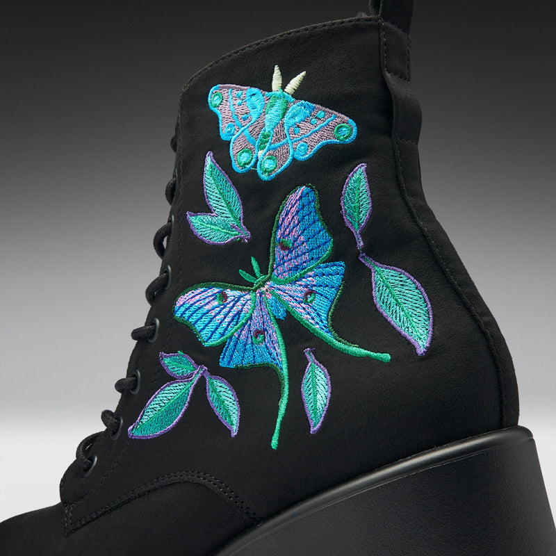 Black boot with colorful butterfly and leaf embroidery on a gradient background