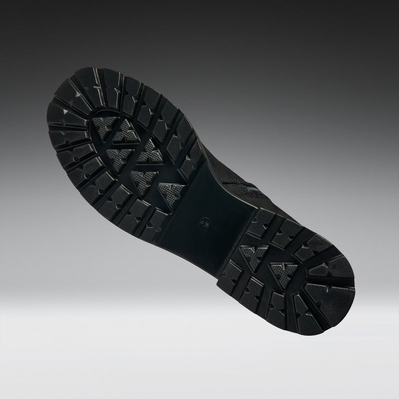 Close-up of a black boot sole on a gradient gray background