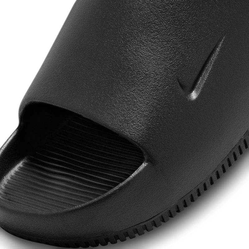 Black slide sandal close-up of textured upper, swoosh detail, and side tread