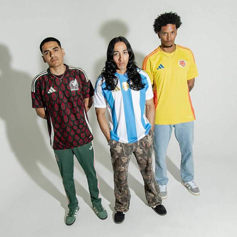 Men's grey low-top sneakers with white stripes and gum sole worn by model group