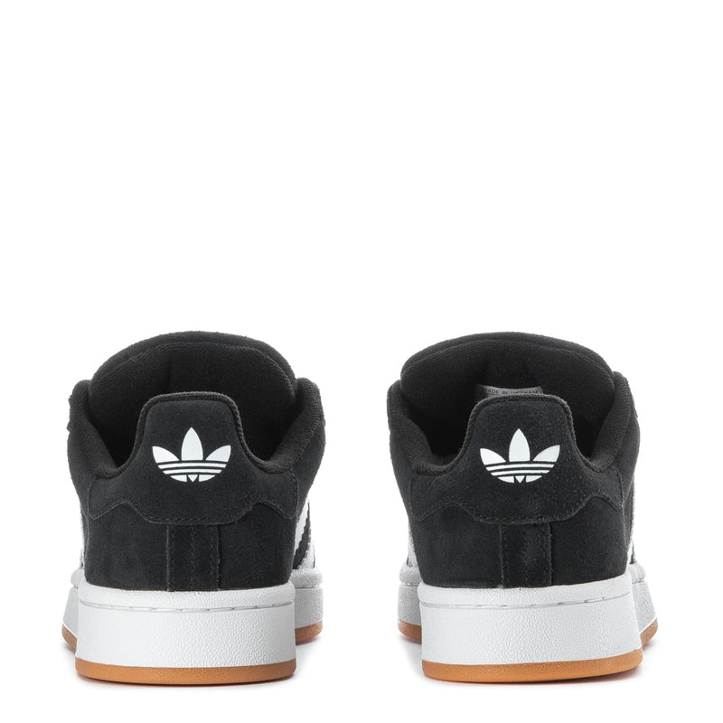 Youth black low-top sneakers with white trefoil logo and gum outsole edge