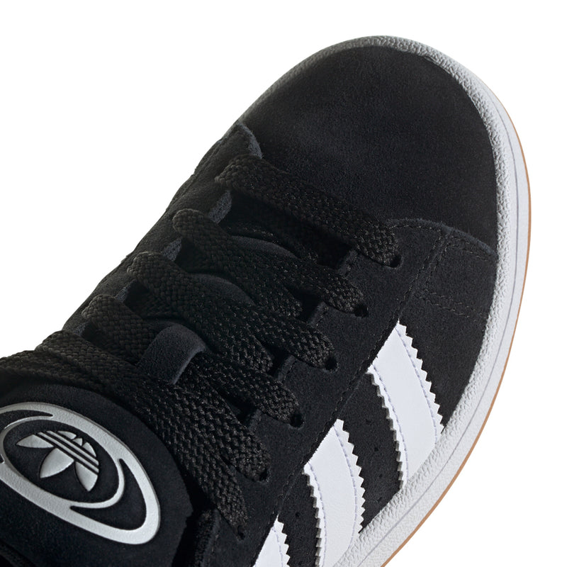 Youth black suede sneaker close-up with 3 white stripes and lace eyelets