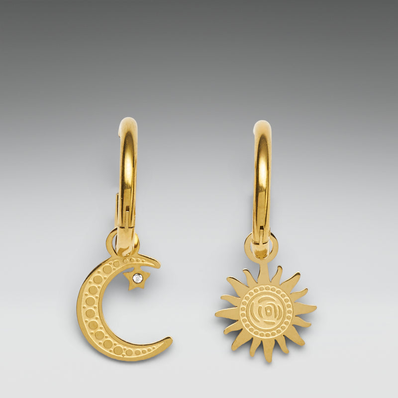 Gold earrings with moon and sun designs on a gray background