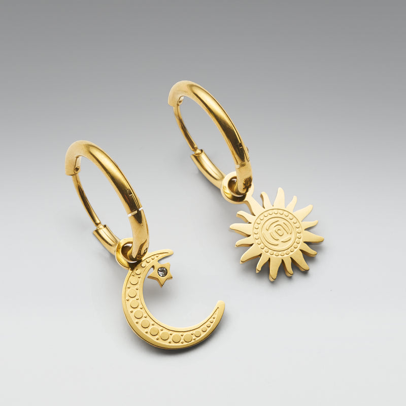 Gold hoop earrings with moon and sun designs on a gray background
