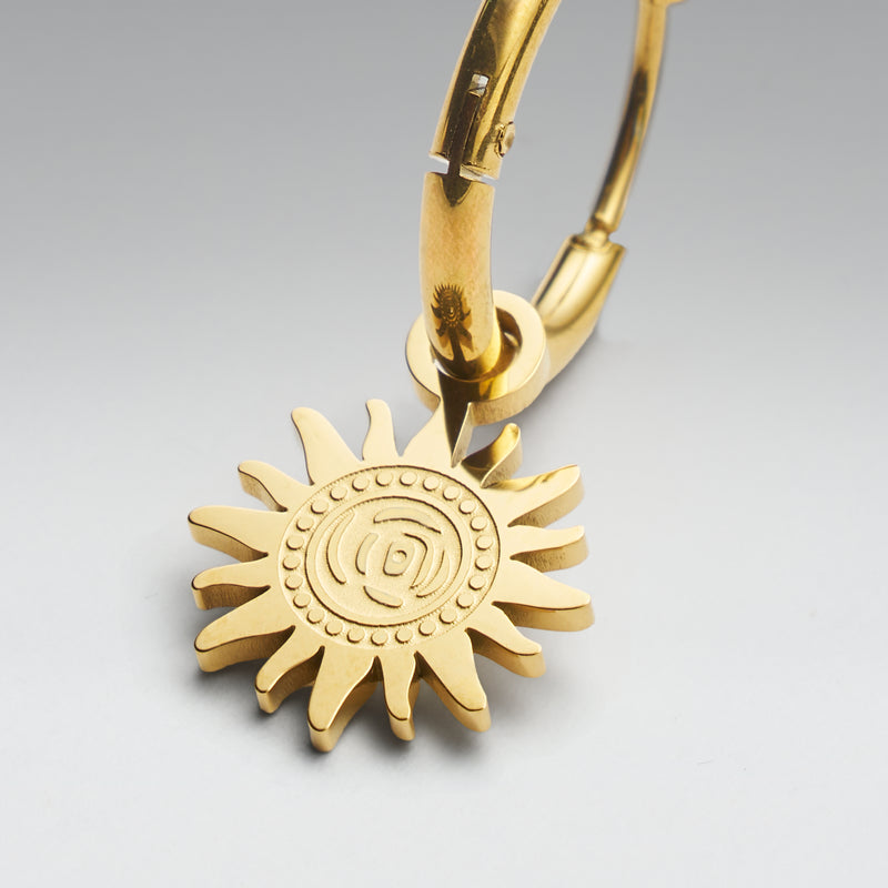 Gold sun-shaped keychain on a gray background