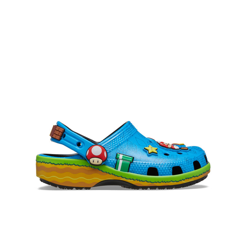 Youth blue clog with green/yellow sole, cartoon game patches, ventilation holes.
