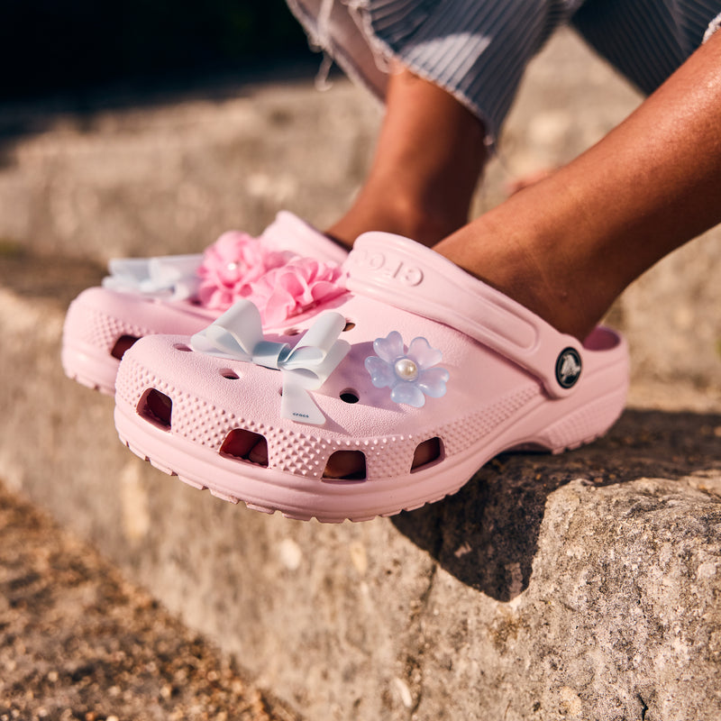Light pink youth clog with side perforations, flower charm, and ventilation holes