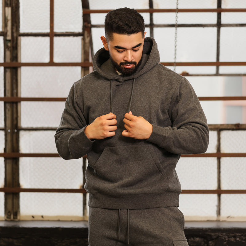 Men's charcoal fleece hoodie worn; drawstring hood and kangaroo pocket visible.