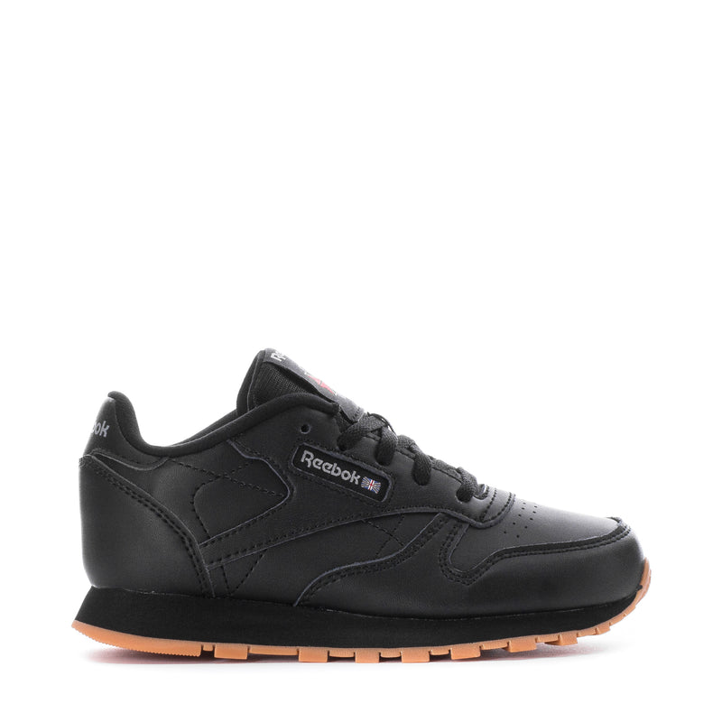 Kids black leather sneaker with Reebok logo and gum rubber sole, front 3/4 view.