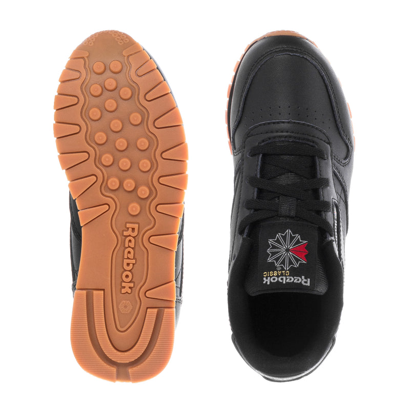 Kids black leather sneakers: gum outsole tread and black heel, pair soles view.