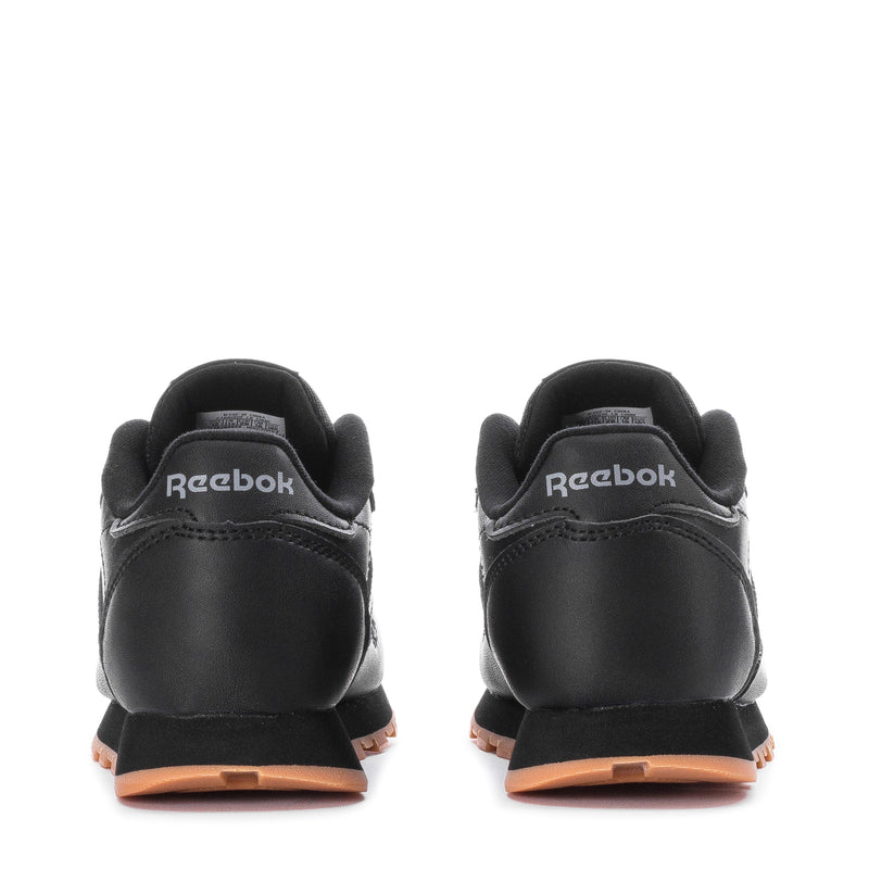 Kids black leather sneakers with Reebok heel logo and gum-toned midsole, back view.