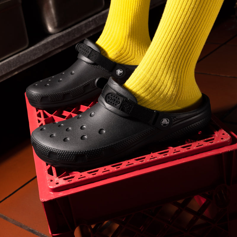 Black slip-resistant clogs on a red platform with yellow socks