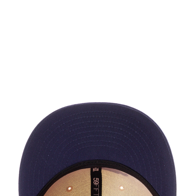 Navy baseball cap brim close-up with textured stitching and partial interior badge