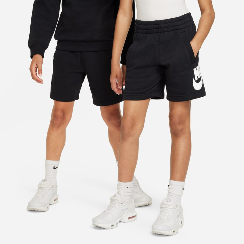 Youth black shorts with white Nike swoosh on side, worn with socks and sneakers