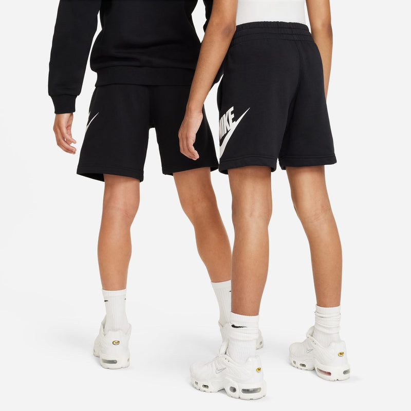Youth black shorts with white Nike swoosh on side, worn with crew socks and shoes