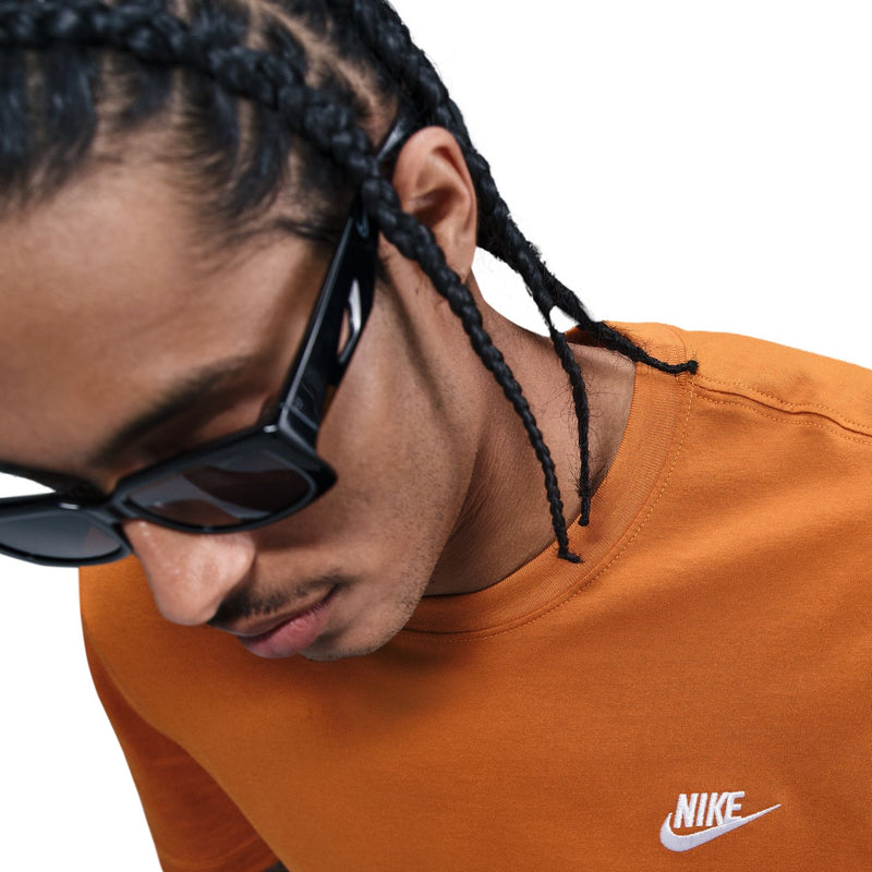 Orange crewneck T-shirt close-up with Nike logo on chest.