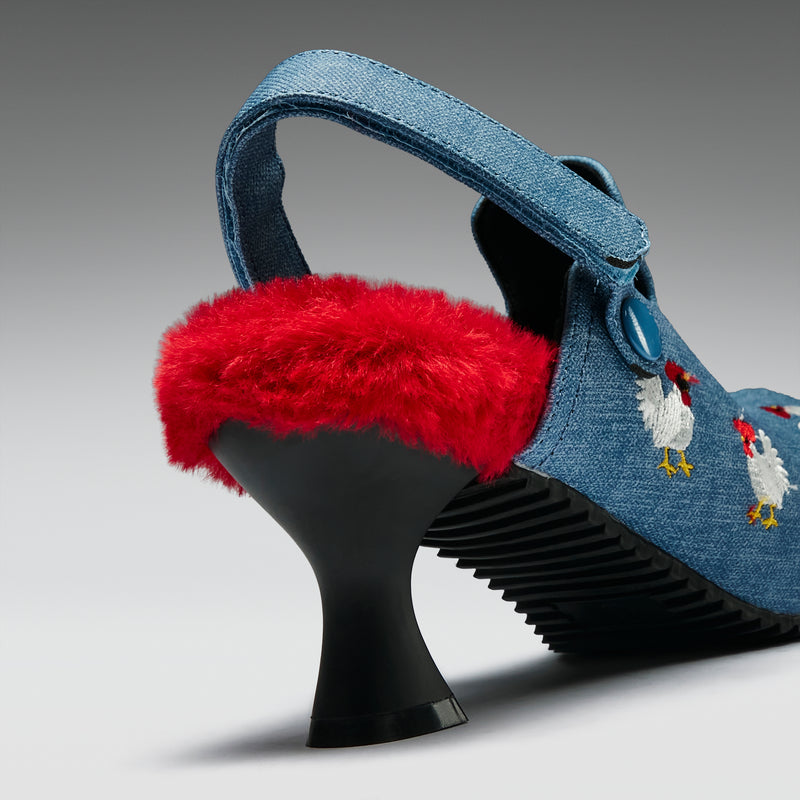 Denim high-heeled shoes with red fur trim on a gray background