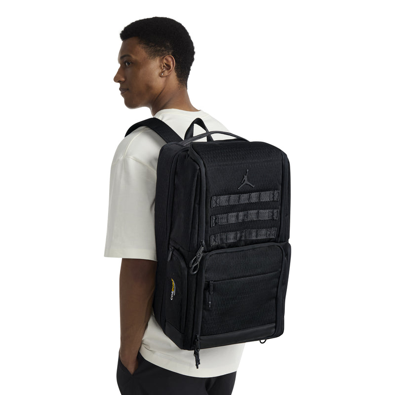 Black backpack worn on back, front patch panel and padded shoulder straps