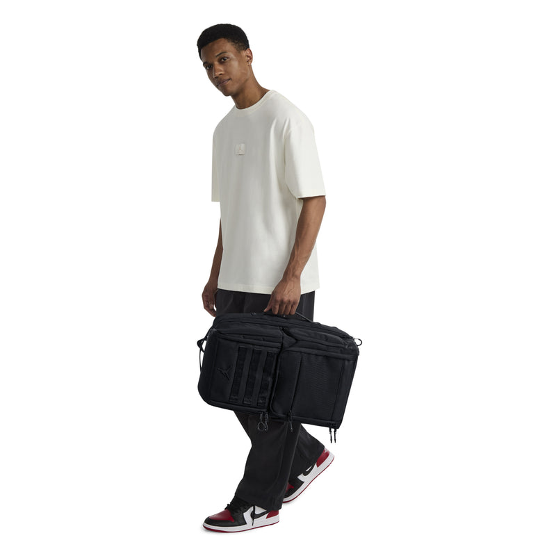 Black backpack carried by model, front patch panels and zip front pocket