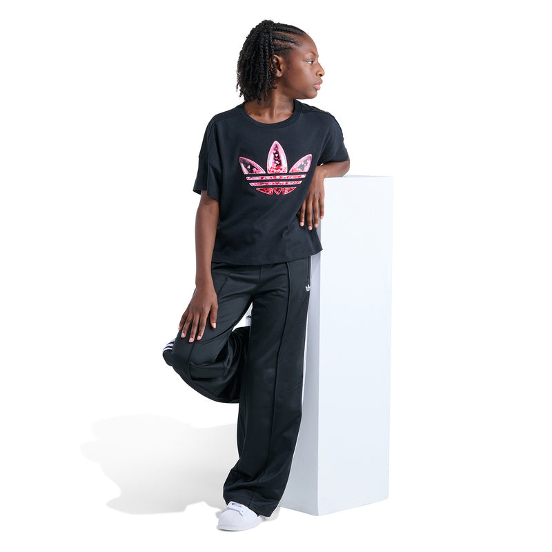 Youth black graphic tee with pink confetti trefoil front design, worn with joggers