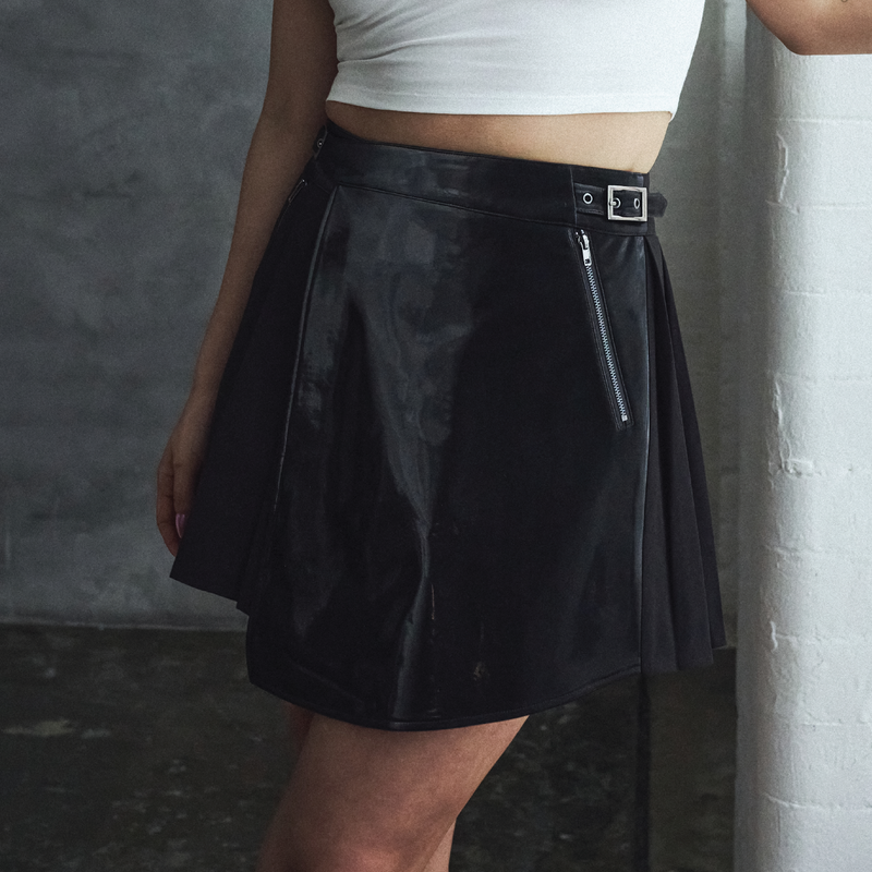 Person wearing a black skirt with zippers on a gray background