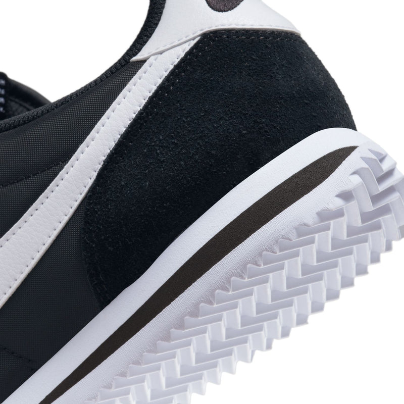 Close-up of black sneaker side with white Swoosh and textured sole