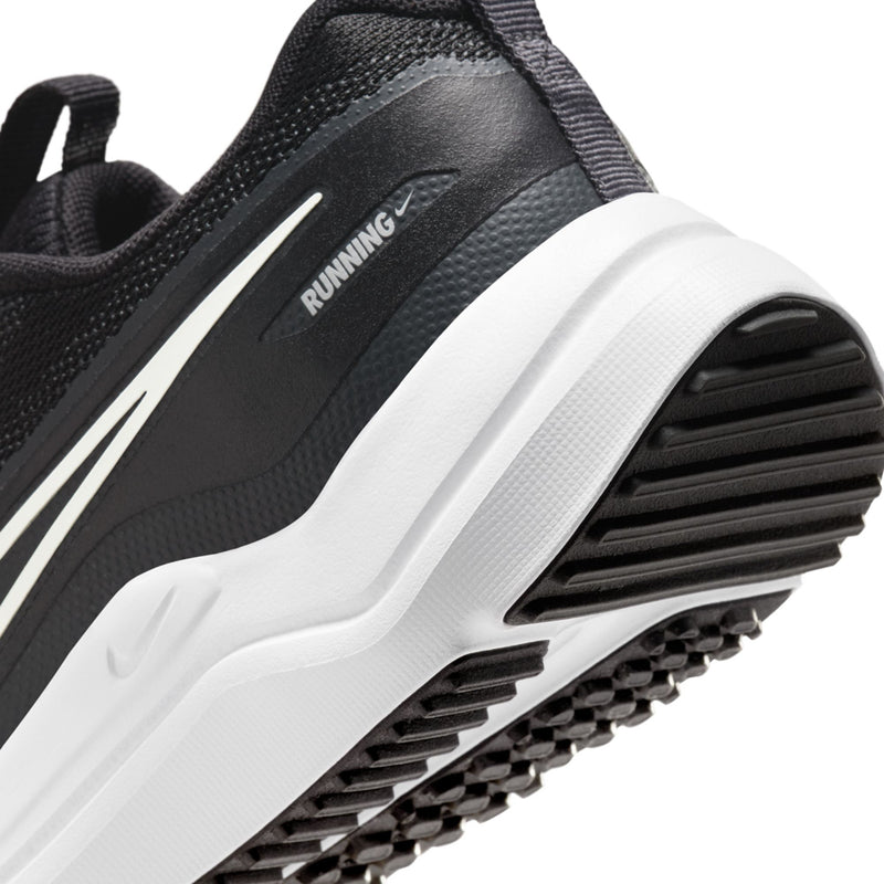 Close-up youth shoe midsole and outsole tread with black grooves and white frame