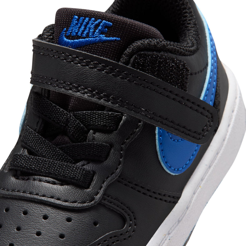 Kids' black sneaker upper close-up with blue swoosh, stitched laces, velcro strap
