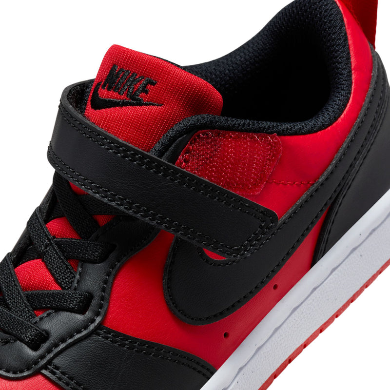 Kids sneaker upper close-up with red tongue lining, black swoosh, and lace eyelets