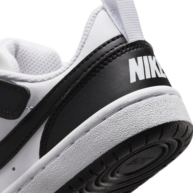 Close-up of kids low-top sneakers, Nike logo on black strap and textured white midsole