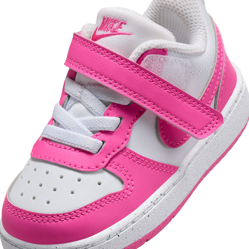 Toddler sneaker close-up with white leather, fuchsia strap, lace tabs, and Nike swoosh.