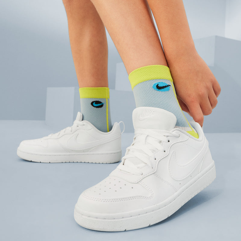 White youth sneakers worn with neon yellow ankle socks
