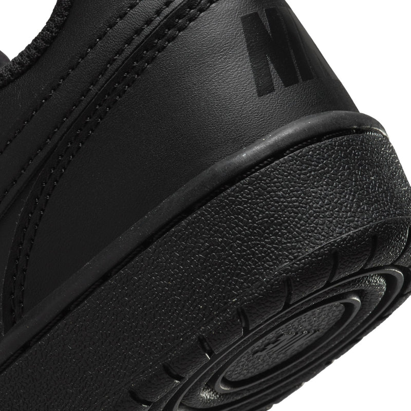 Black youth sneaker sidewall close-up with Nike swoosh and textured rubber outsole edge.