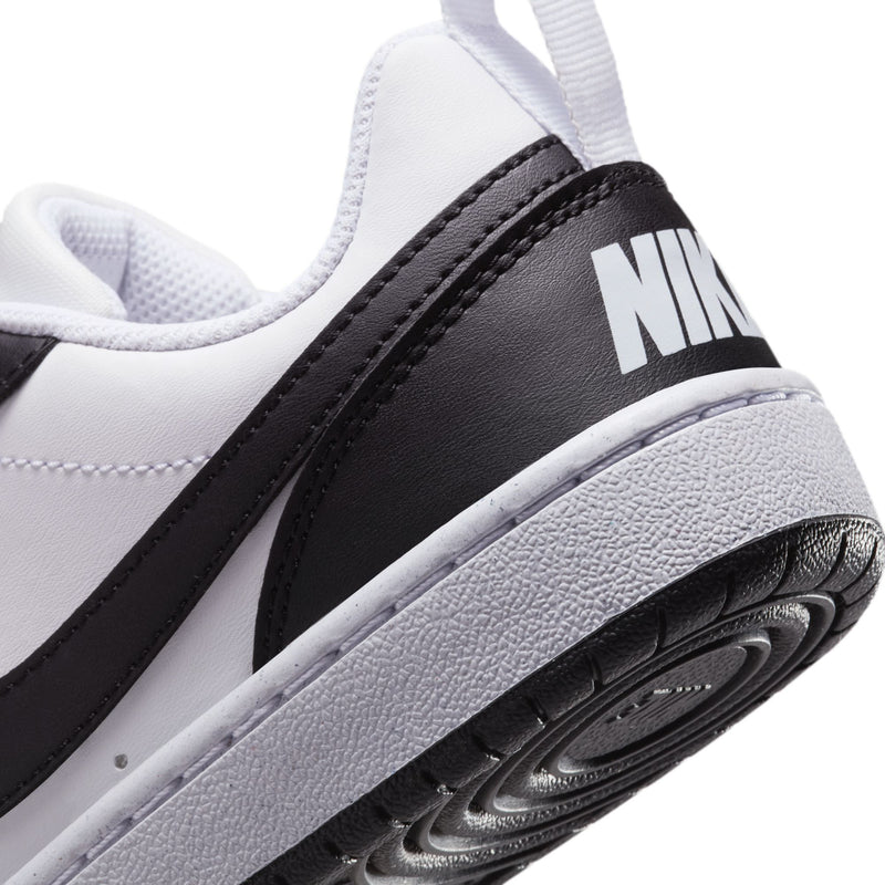 Close-up of youth sneaker side panel with black stripe, NIKE text, and textured sole