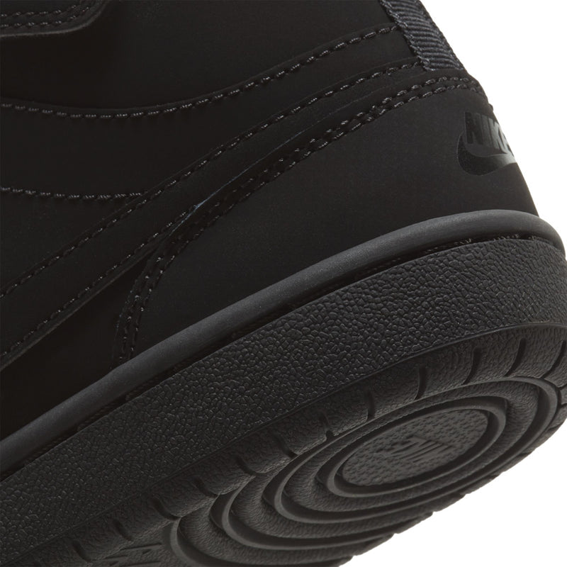 Kids black mid-top sneaker side close-up with textured rubber outsole, stitched panel