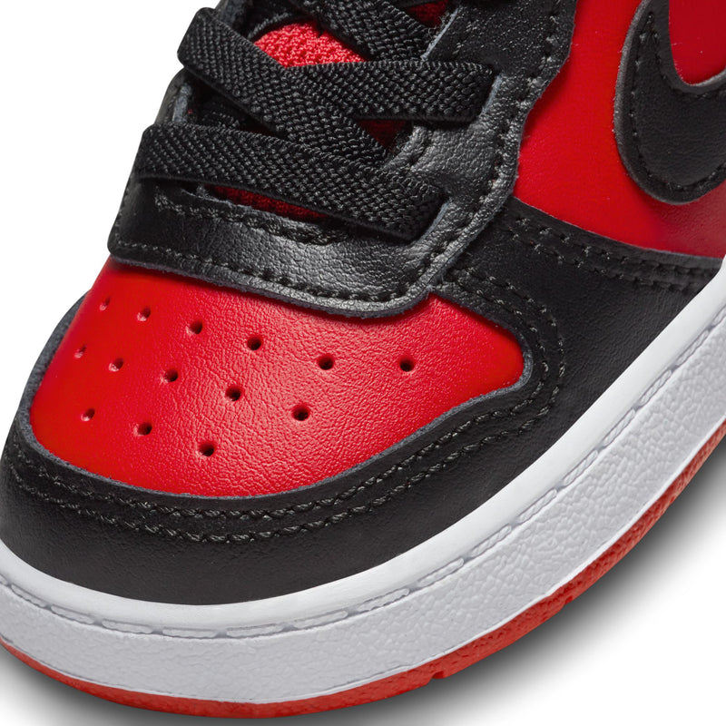 Toddler sneaker close-up: red toe with black swoosh and perforated ventilation holes