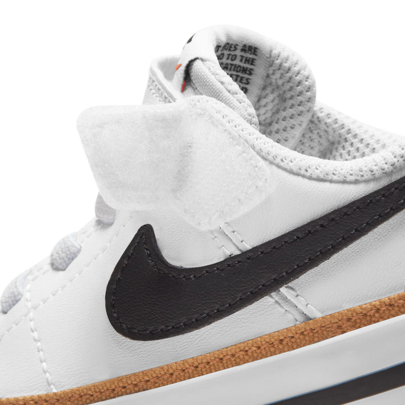 Toddler sneaker close-up, white upper with black swoosh and tan rubber outsole