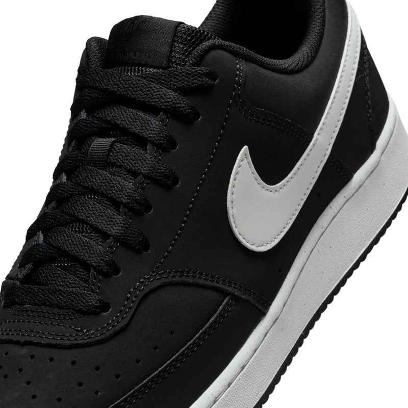 Close-up of black low-top sneaker with white swoosh and lace-up panel