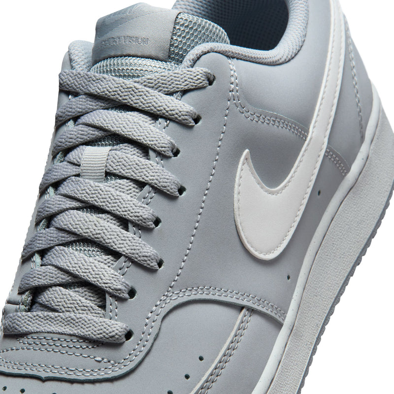 Close-up of light gray sneaker with textured laces and white swoosh