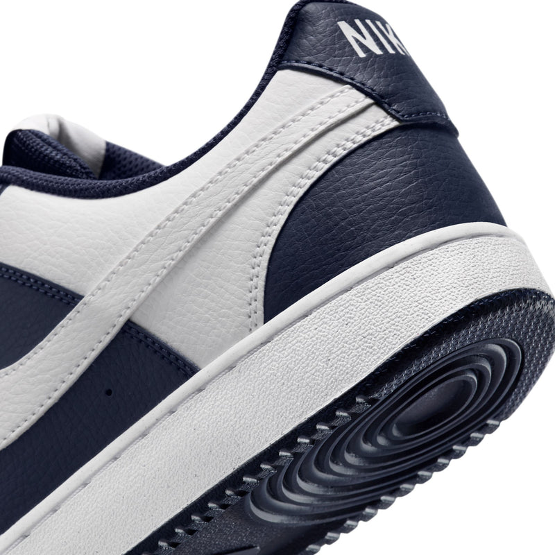 Men's low-top sneaker side close-up with leather texture, navy trim, and white midsole.