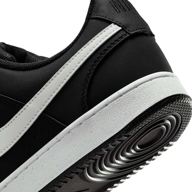 Close-up of black sneaker sole with white side stripe and tread details