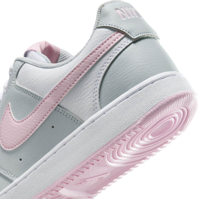 Women’s low-top sneakers in light gray with pink swoosh and white rubber sole.