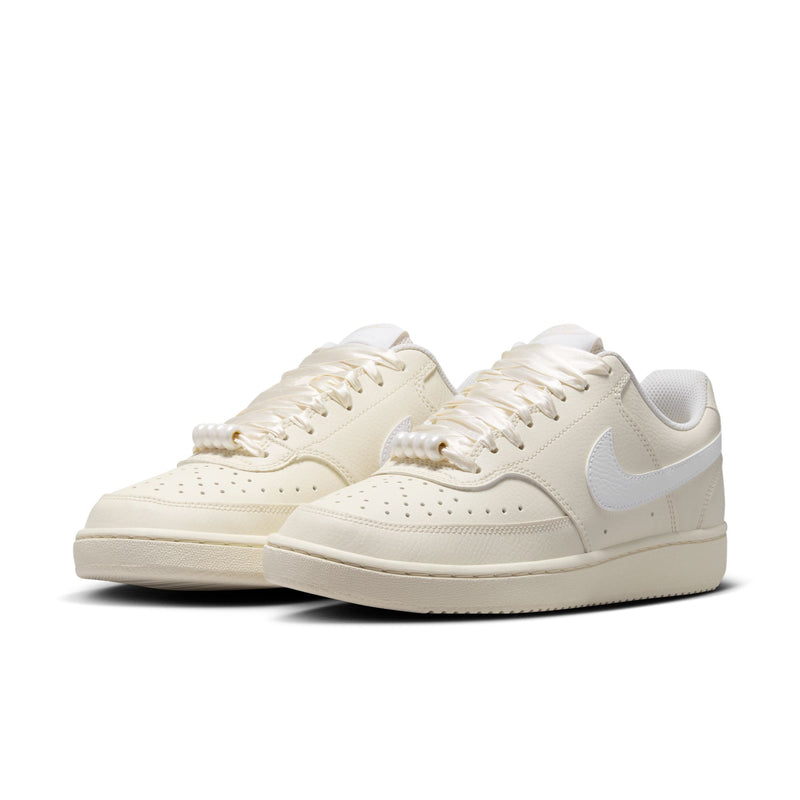 Pair of women’s low-top cream Nike sneakers with light blue swoosh and lace-up uppers