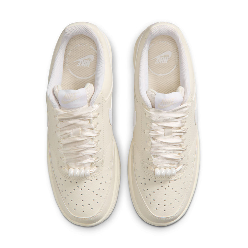 Top view of women’s cream Nike low-top sneakers with white laces and perforated toe