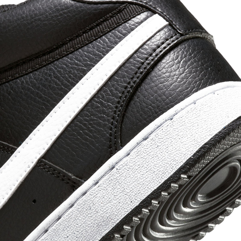 Black sneaker side close-up with white stripe and embossed Swoosh